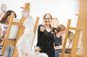 Claire Pope demonstrates perspective among students at easels