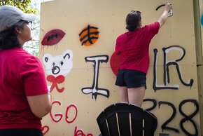 Students spray painting LR-themed images on the graffiti wall