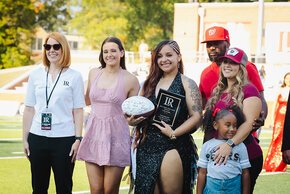 Summer McGee with Avelyn Paulino and family on the football field at homecoming