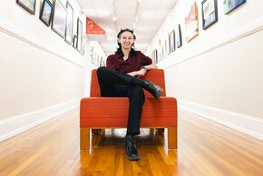 Ethan Craig sits in a red-orange chair in a hallway in the Mitford Museum