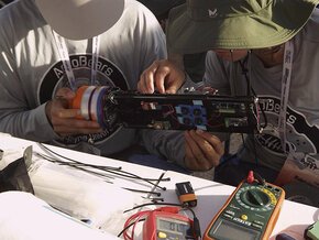 Two rocket team members fine tune a piece of equipment before launch