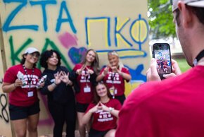 Members of two sororities pose for a photo in front of the graffiti wall