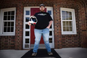 Kevin Miller holding his helmet in front of Schaeffer Hall