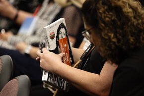 A fan holds multiple copies of McCarthy's books and signing ticket in the audience.