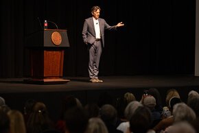 McCarthy standing and gesturing next to the podium on the stage