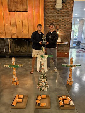 FCA members pose behind their three crosses built from cans.