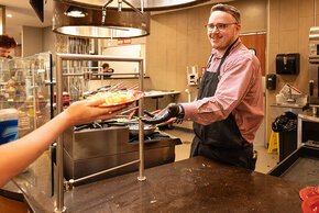 Gray Stone passes a plate to a student on the cafeteria serving line