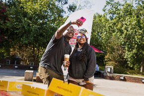 Harry Titus takes a selfie with a student in front of the Donuts with the Dean banner