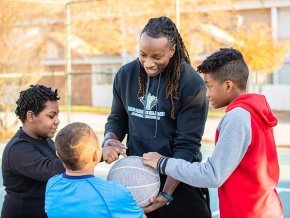 Jamal Stroud playing basketball with children.
