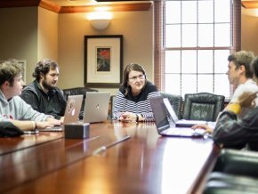 Dr. Lesser with students around a table discussing stocks and the market