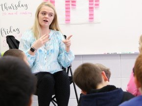 A student teacher interacts with elementary kids in front of the classroom.