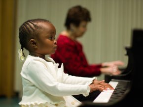 A young girl plays the piano