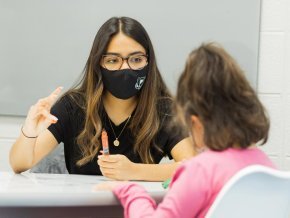 Geraldine Ledezma-Garcia works with an elementary student in classroom at table