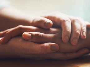 Two hands being held on table comforting someone