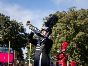 Members of the marching band play trumpets outside on the football field