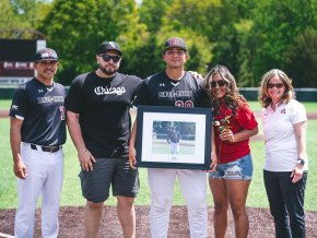 Five people stand together on a baseball field