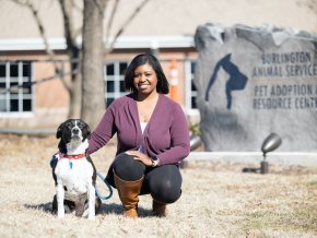 Amber Currie kneels outside of the an animal shelter with her dog