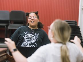 A student sings in an indoor choral classroom