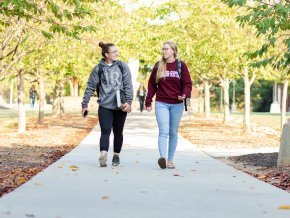 Two students walk and chat outside