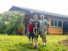 Four people stand outside in front of a house on a sunny day