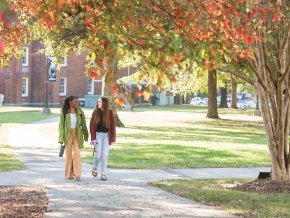 Two students walk outside on a fall day