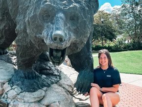 Kristi Hilton poses with the black bear statue on campus