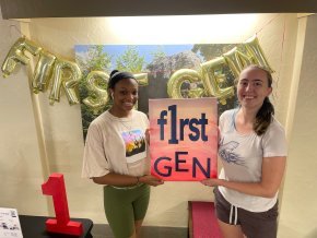 Two students hold up a sign indoors