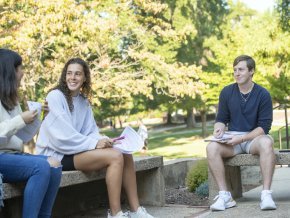 Three students sit outside and talk