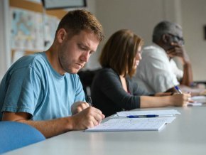 Seminary students writing at table in classroom