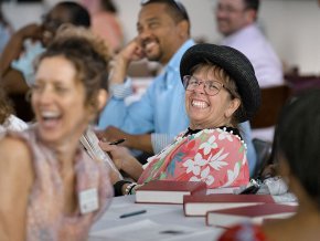 LTSS professors and alumni smiling and laughing around tables during an event.