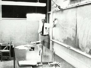 Charles Cooke in front of a chalkboard in the lab in 1984