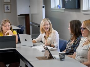 Susan McArver collaborates with students around a conference table