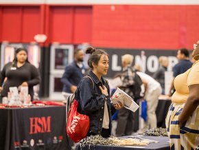 Student talking to a representative at career fair with other booths visible in the background