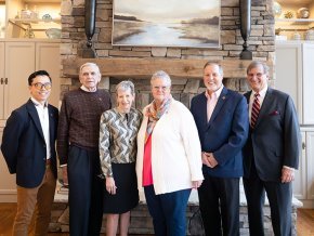 Five alumni award winners and President Whitt stand in front of a stone wall.