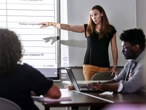 Taylor Newton gestures to a projected chart in front of a classroom