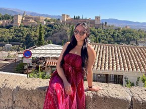Lina San Juan Martinez sits on a wall with Granada in the background