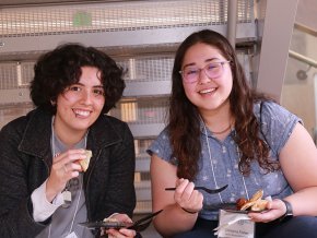 Demmi Ramos and Christina Fisher eating lunch in a hallway at NCAS meeting.