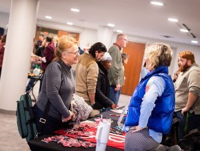 An LTSS student chats with a staff member over a table at a student services fair