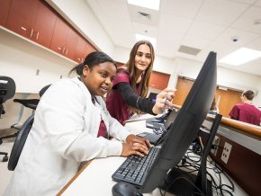 Two students review a computer screen in a simulated hospital station