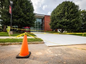 Cones and caution tape around fresh concrete in front of PE Monroe auditorium
