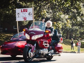 Joe Shumate, with Kathleen Tucker in the sidecar, rides a red Honda Gold Wing in the 2025 Homecoming Parade
