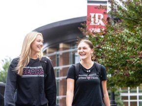 Students walking on campus in front of LR banner and George Hall