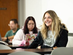 Two students working together in foreground, a third with another task in background