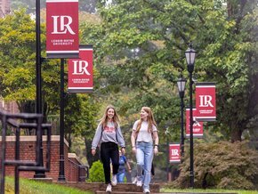 LR students walking along sidewalk on campus with LR banners in background