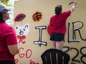 Students spray painting LR-themed images on the graffiti wall