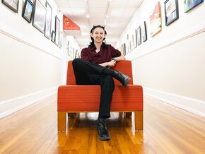 Ethan Craig sits in a red-orange chair in a hallway in the Mitford Museum