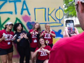 Members of two sororities pose for a photo in front of the graffiti wall