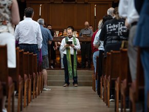 Pastor Vern, framed by congregation, reads during chapel service