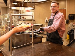 Gray Stone passes a plate to a student on the cafeteria serving line