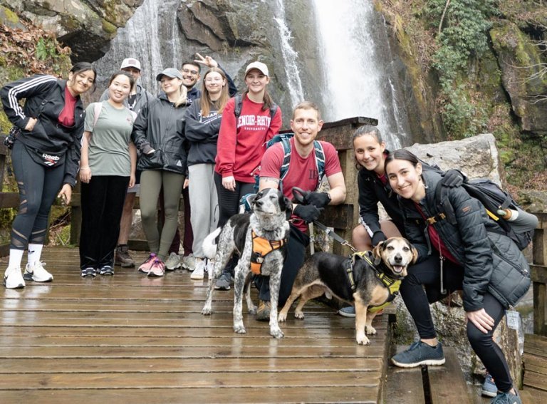 Group of LR Outdoor Adventure Club students pose for a photo in front of a waterfall while hiking